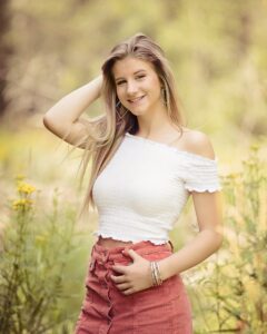 Sioux Falls Senior posing in field at sunset with flowers